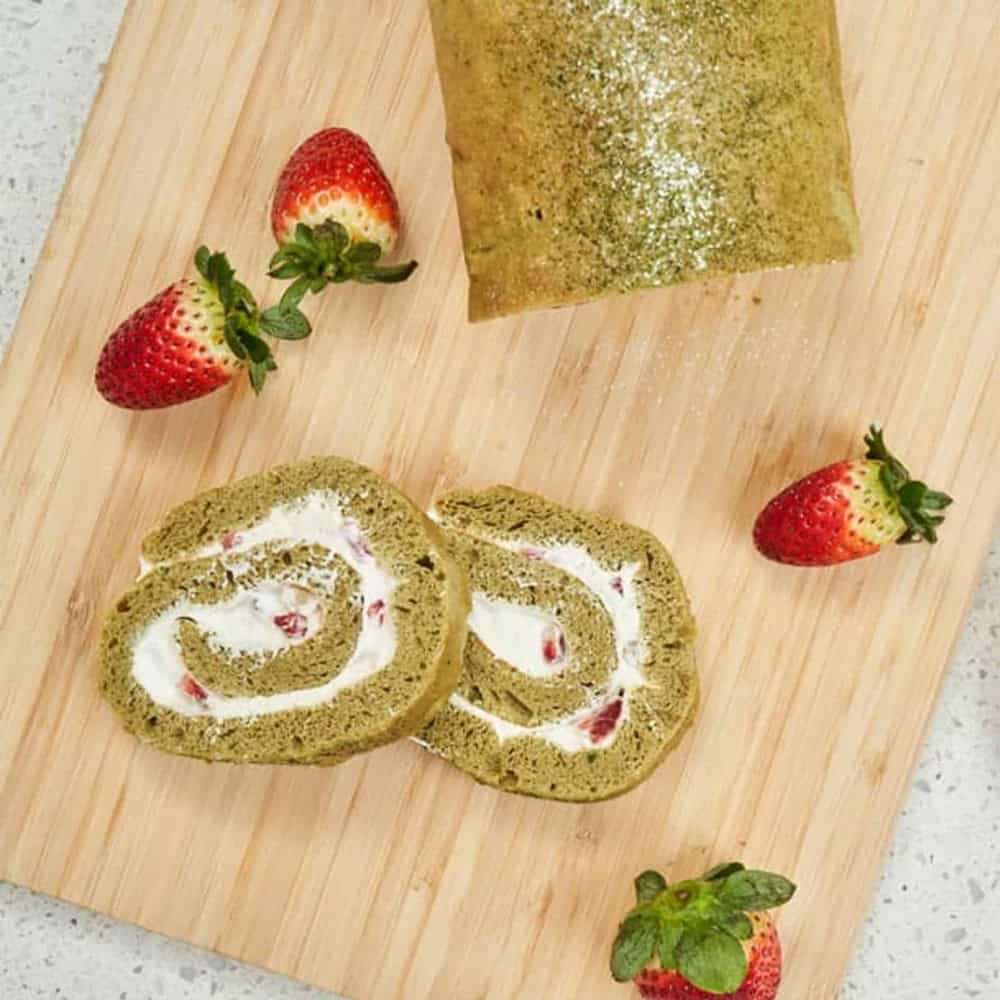 Sliced matcha swiss roll cake filled with cream and strawberries, demonstrating baking uses for the bulk 1Kg Matcha Maiden.