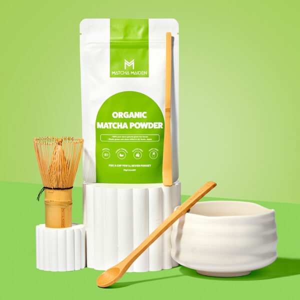 Matcha Maiden Complete Kit with pouch of organic matcha powder alongside traditional bamboo whisk, scoop, spoon, and a white ceramic bowl.