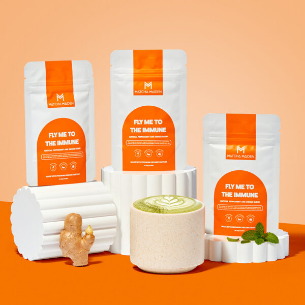 Matcha Maiden Fly Me To The Immune Bundle featuring three pouches displayed on white ribbed pillars, alongside fresh ginger.