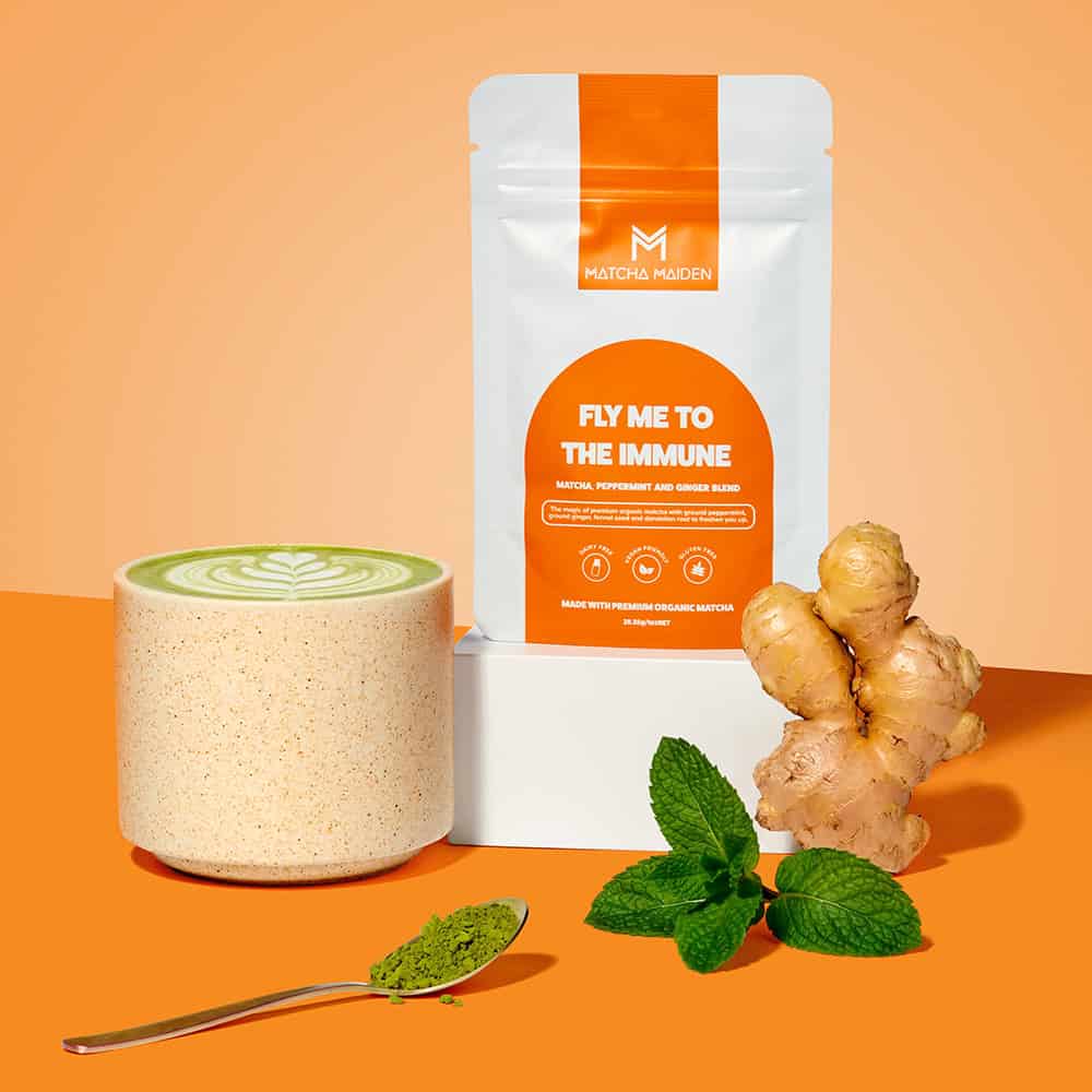Matcha Maiden Fly Me To The Immune 28.35g pouch by fresh ginger root, mint leaves, and a hot matcha latte.