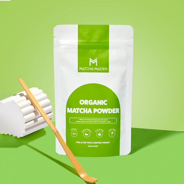 Matcha Maiden 70g organic matcha pouch with traditional bamboo scoop on a bright green background.