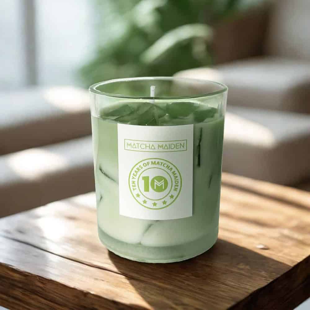 Matcha Maiden iced matcha latte candle on rustic wooden coffee table in a cozy, sunlit living room.