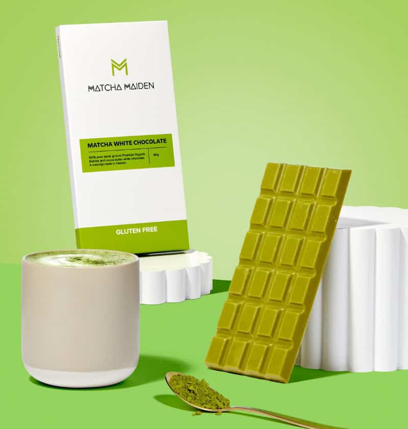 Matcha Maiden gluten-free matcha white chocolate bar, packaging, matcha latte, and matcha powder on a spoon.